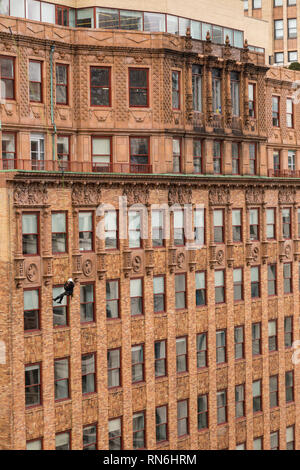 Ingénieur industriel descendre en rappel le long du côté d'un immeuble sur l'inspection des structures, New York City, USA Banque D'Images