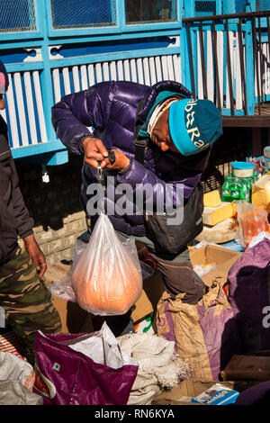 Np984 Népal, Namche Bazar, Marché, pesant de trader un grand sac en plastique de lentilles à la vente, à l'aide de la balance à ressort Banque D'Images
