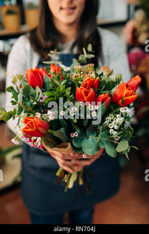 Fleuriste femme fait un bouquet de tulipes orange sur table en bois Banque D'Images