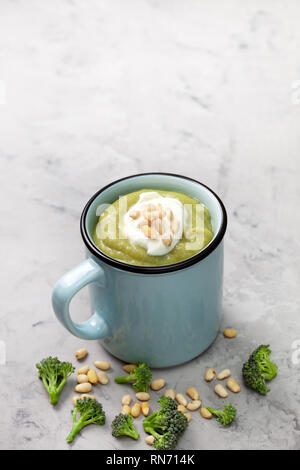 Purée de brocoli soupe avec les pignons de pin dans une tasse de brocoli frais, bleu sur fond gris Banque D'Images