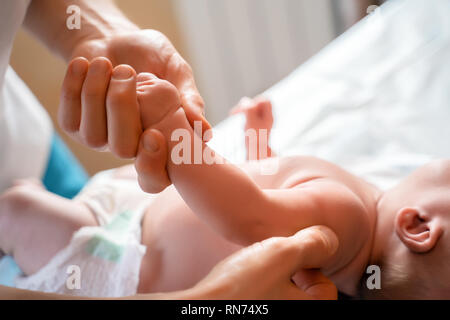 Photo de mains de massothérapeute et bébé sur table. Banque D'Images