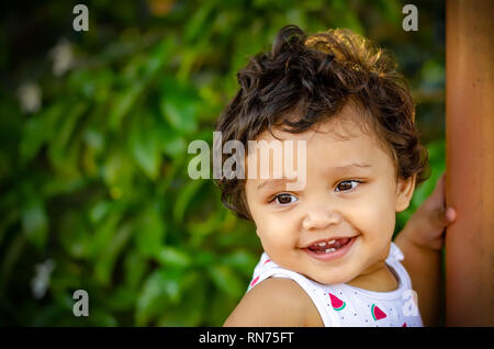 Closeup portrait of a happy Indian girl dans le parc avec un fond vert. Banque D'Images