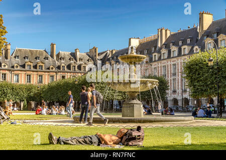 Des gens assis et bains de soleil près de la la fontaine sur une chaude journée d'été à la Place des Vosges, dans le quartier le quartier du Marais à Paris . Banque D'Images