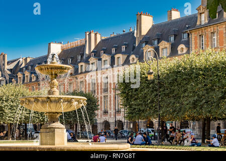 Personnes assises près de la fontaine lors d'une chaude journée d'été à la place des Vosges, dans le quartier à la mode du Marais de Paris, France Banque D'Images