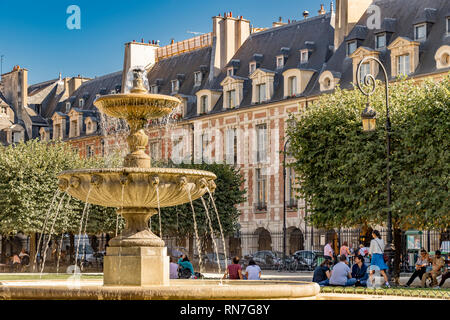 Les gens assis près de la la fontaine sur une chaude journée d'été à la Place des Vosges, dans le quartier le quartier du Marais à Paris Banque D'Images