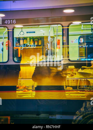 Les citoyens de boire du café dans un bar de Milan dans la nuit. La Lombardie, Italie. Vue à travers le reflet de la fenêtre d'un tramway. Banque D'Images