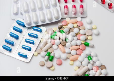 Médicaments colorés et comprimés ou gélules en plaquettes sur fond blanc. Vue d'en haut. Banque D'Images