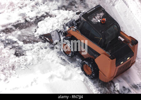 Une petite machine de déneigement urbain travaille dans la cour d'un immeuble résidentiel. Vue de dessus. Selective focus Banque D'Images