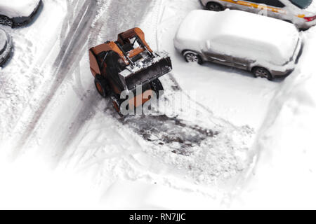 Une petite machine de déneigement urbain travaille dans la cour d'un immeuble résidentiel. Vue de dessus. Selective focus Banque D'Images