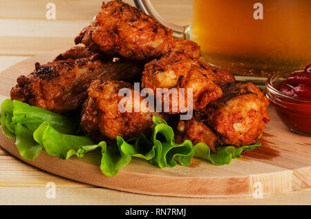 Les ailes de poulet dans la chapelure avec sause et bière sur une planche à découper Banque D'Images