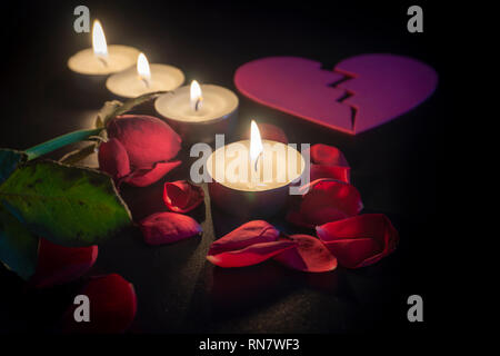 Quatre plateau bougies et pétales de rose rouge dans le noir avec une faible profondeur de foyer Banque D'Images