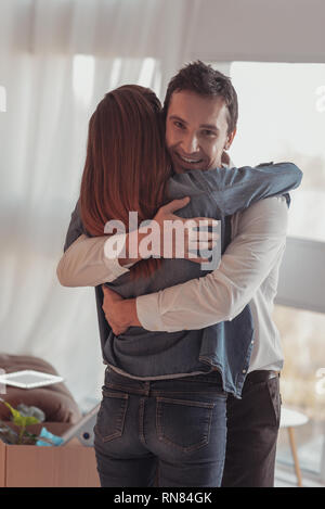 Une femme l'homme. Belle Lumière hearted mari serrant ses jolie jeune femme et l'expression de joie tandis que looking at camera Banque D'Images