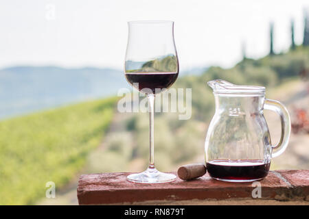Bénéficiant d''un verre de vin rouge à la Toscane, Italie. Vignobles flou en arrière-plan. Banque D'Images