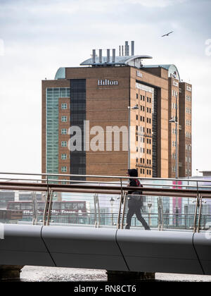 Une figure solitaire marche sur le pied et pont Cycle Lagan. Hôtel Hilton se trouve à l'arrière-plan Banque D'Images