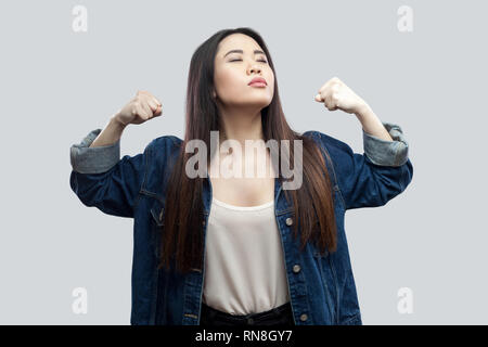 Je suis fort et indépendant. Portrait de fiers satisfait belle brune asian young woman in casual veste bleue et un miroir avec permanent soulevées ar Banque D'Images