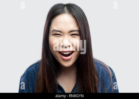 Closeup portrait of crazy funny belle brune asian young woman in casual veste en jean bleu avec un miroir et permanent à la caméra à l'intérieur st. Banque D'Images