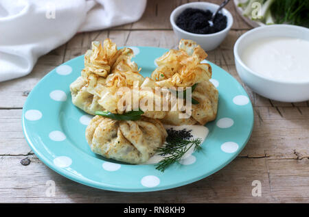 Crêpes farcies de sacs de hareng, servi avec caviar, crème aigre et aneth sur un fond de bois. De style rustique, selective focus. Banque D'Images