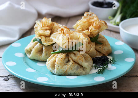 Crêpes farcies de sacs de hareng, servi avec caviar, crème aigre et aneth sur un fond de bois. De style rustique, selective focus. Banque D'Images