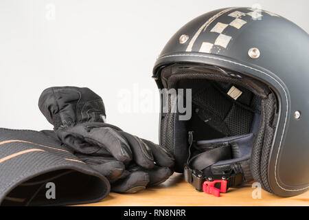 L'équipement de protection moto - face ouverte casque, gants et une ceinture sur un fond de bois. Banque D'Images