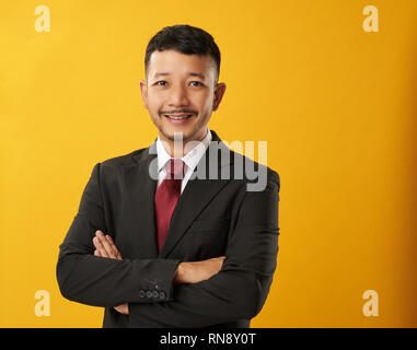 Guy portriat asiatique avec les bras croisés fond couleur Banque D'Images