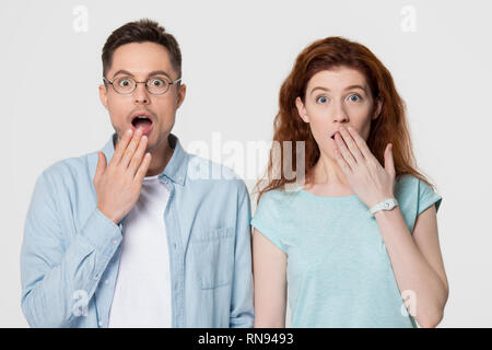 Choqué stupéfié couple couvrant la bouche avec mains looking at camera Banque D'Images