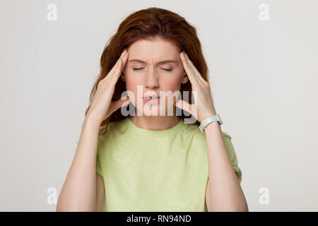 Femme rousse a souligné se sentir forts maux de tête isolé sur fond blanc Banque D'Images