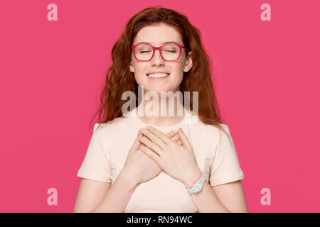 Professionnels reconnaissant red-haired woman holding hands on poitrine sentir gratitude Banque D'Images