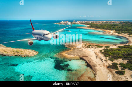 C'est avion survolant la mer et îles au lever du soleil en été. Paysage avec avion passager blanc, mer, plage, ciel et d'azur de l'eau. Pas blanc Banque D'Images