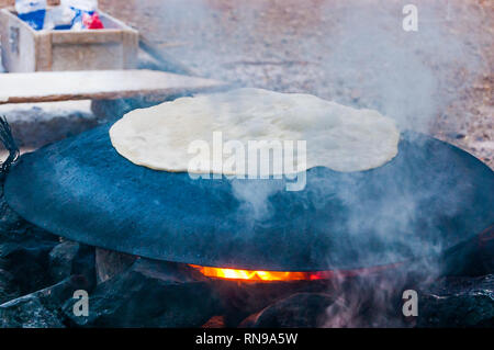 Bédouin traditionnel gâteau cuisson sur plaque de métal sphère semi ronde en feu à Eilat, Israël Banque D'Images