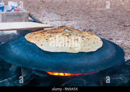 Bédouin traditionnel gâteau cuisson sur plaque de métal sphère semi ronde en feu à Eilat, Israël Banque D'Images