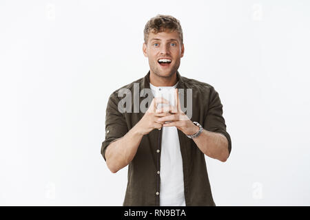 Mignon et joyeux sourire dit guy comme prenant tourné sur smartphone le regard souriant joyeusement à la tenue de l'appareil photo, photographier sur téléphone mobile cellulaire Banque D'Images