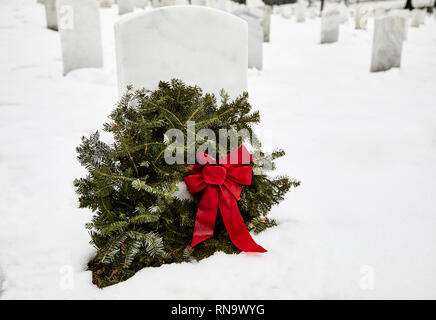 Pierre tombale dans un cimetière avec une couronne faite de branches de pins en hiver avec de la neige au sol Banque D'Images