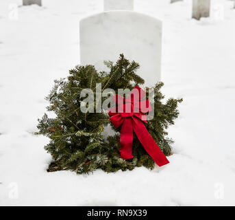 Pierre tombale dans un cimetière avec une couronne faite de branches de pins en hiver avec de la neige au sol Banque D'Images