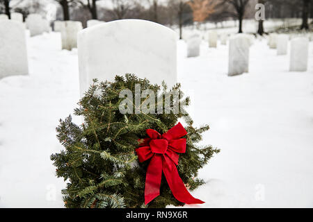 Pierre tombale dans un cimetière avec une couronne faite de branches de pins en hiver avec de la neige au sol Banque D'Images