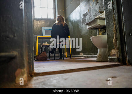 Berlin, Allemagne. Feb 18, 2019. À l'ouverture d'un lieu d'apprentissage parascolaires dans une cellule de l'ex-RDA police prison dans Keibelstraße à Berlin, une lycéenne en apprend davantage sur l'histoire de l'immeuble. Selon le sénateur, jeunes il sera en mesure de traiter l'état d'arbitraire et de la répression dans la RDA à l'avenir. Visites guidées de l'édifice sont également prévues pour les visiteurs intéressés. La prison était vide depuis des années, l'utilisation avait été mal pendant une longue période. Credit : Jörg Carstensen/dpa/Alamy Live News Banque D'Images