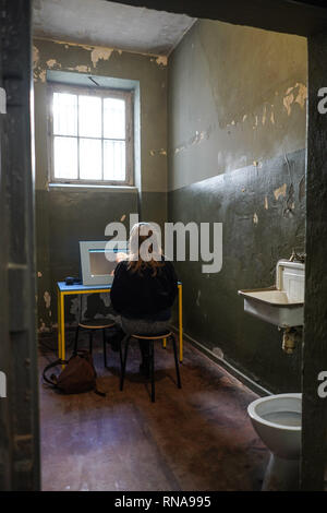 Berlin, Allemagne. Feb 18, 2019. À l'ouverture d'un lieu d'apprentissage parascolaires dans une cellule de l'ex-RDA police prison dans Keibelstraße à Berlin, une lycéenne en apprend davantage sur l'histoire de l'immeuble. Selon le sénateur, jeunes il sera en mesure de traiter l'état d'arbitraire et de la répression dans la RDA à l'avenir. Visites guidées de l'édifice sont également prévues pour les visiteurs intéressés. La prison était vide depuis des années, l'utilisation avait été mal pendant une longue période. Credit : Jörg Carstensen/dpa/Alamy Live News Banque D'Images