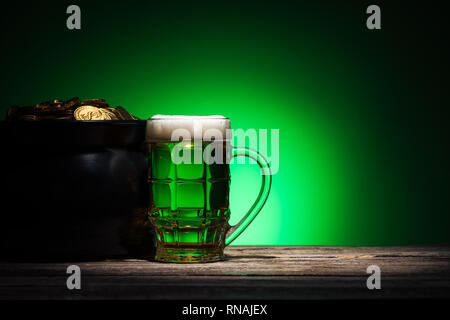 Verre de bière près de pot avec de l'or sur St Patricks day sur fond vert Banque D'Images