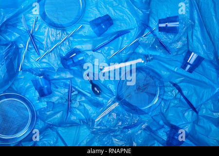 Vue de dessus du sac en polyéthylène froissé bleu avec des bouteilles en plastique, tasses, assiettes, couteaux, cuillère éponge ang Banque D'Images