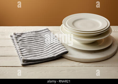 Pile de plaques blanches et serviette rayée en coton blanc sur la surface en bois Banque D'Images