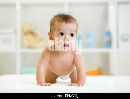 Funny baby boy portée couche crawls in nursery Banque D'Images