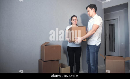 Heureux Couple Carrying Cases dans nouvelle maison le jour du déménagement Banque D'Images
