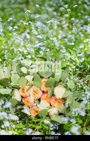 Beau bouquet de mariage est allongé dans l'herbe. Bagues de fiançailles sont sur les fleurs. Les couleurs orange de l'automne et de l'automne en composition florale. Banque D'Images