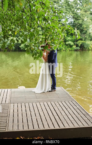 Beau couple de mariage, mariée,groom kissing et posant sur la pirse près du lac Banque D'Images