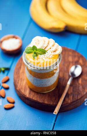 Chia pudding à la mangue dans un pot bleu sur fond de bois. L'été en bonne santé repas vegan Banque D'Images