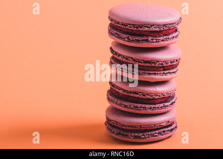 Pile de délicieux macarons sur fond de corail, la couleur de 2019 concept Banque D'Images