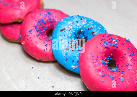 Les beignes glacés bleu et rose avec paillettes sur fond clair, vue rapprochée. Banque D'Images