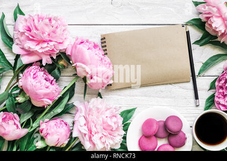 Carte de papier vierge avec fleurs de pivoine rose, macarons et café tasse blanche sur fond de bois. Télévision. vue d'en haut.. la maquette ou mariage womens day compo Banque D'Images