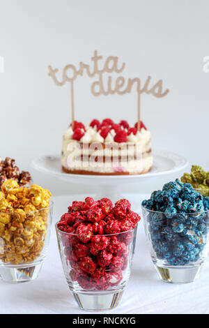 A table avec des verres colorés en pop-corn et des gâteaux dans l'arrière-plan Banque D'Images