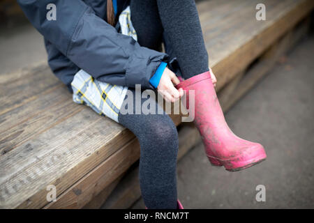 L'école primaire de fille rose tirant sur wellies Banque D'Images