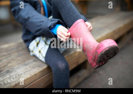 L'école primaire de fille rose tirant sur wellies Banque D'Images